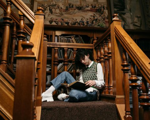 a college student reading a book white sitting on the stairs